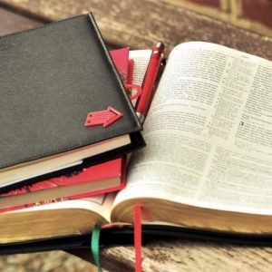 Two notebooks on top of an open Bible