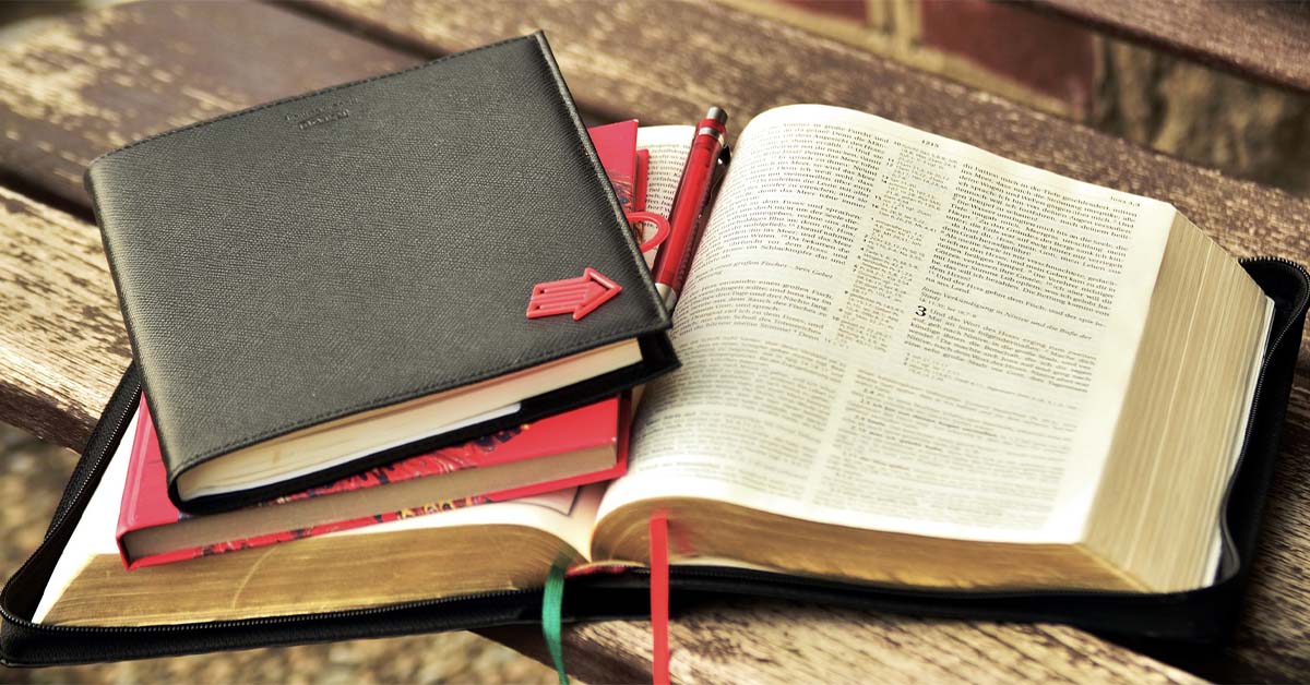 Two notebooks on top of an open Bible